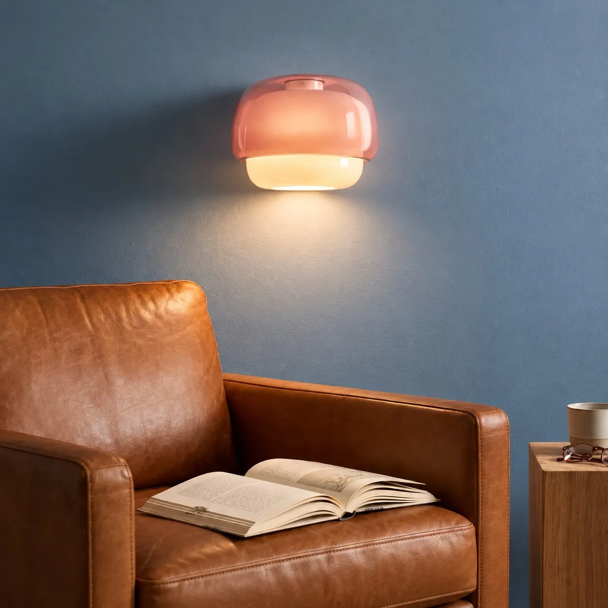 Blush sconce above a leather reading chair