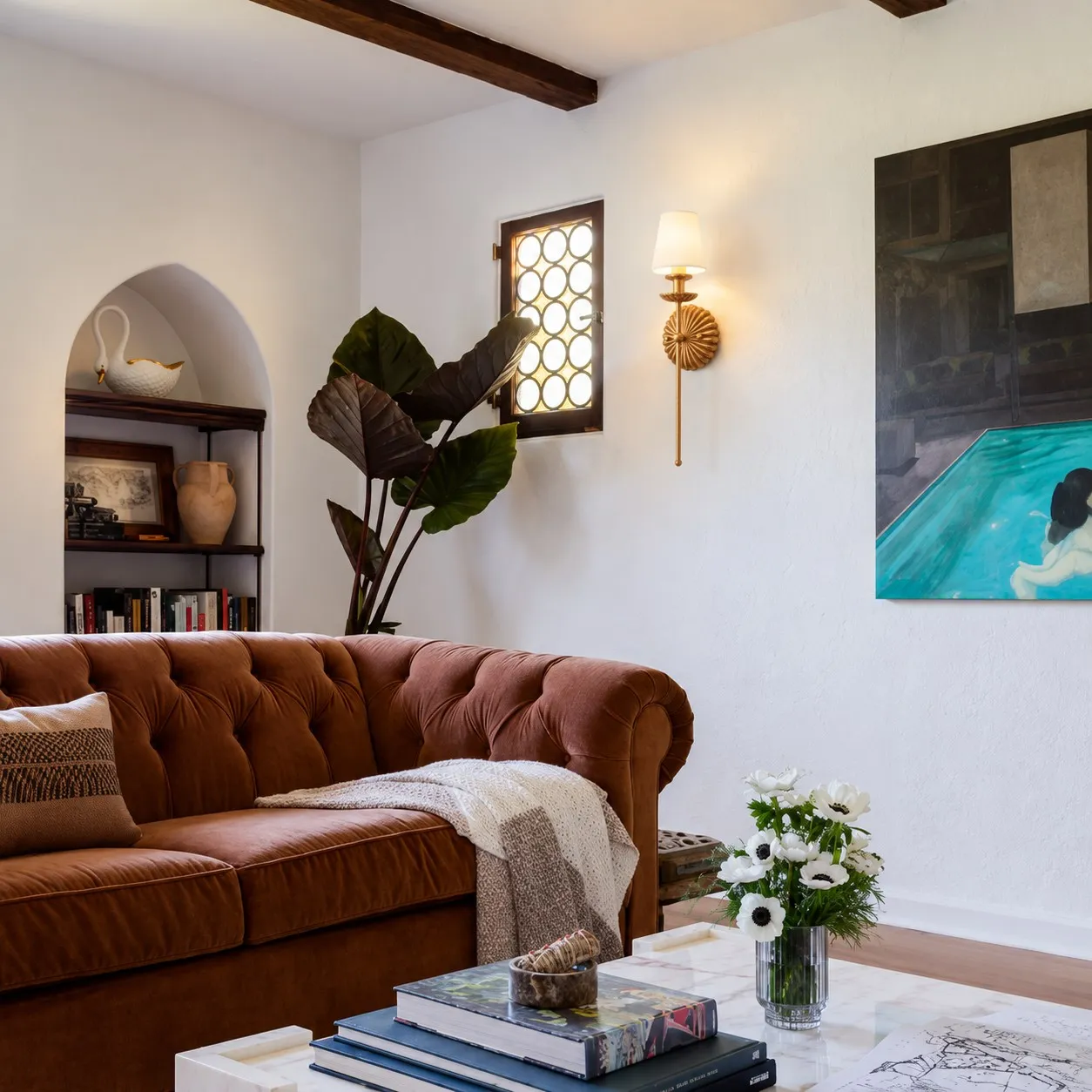Antique gold single wall lamp beside a small window in a living room