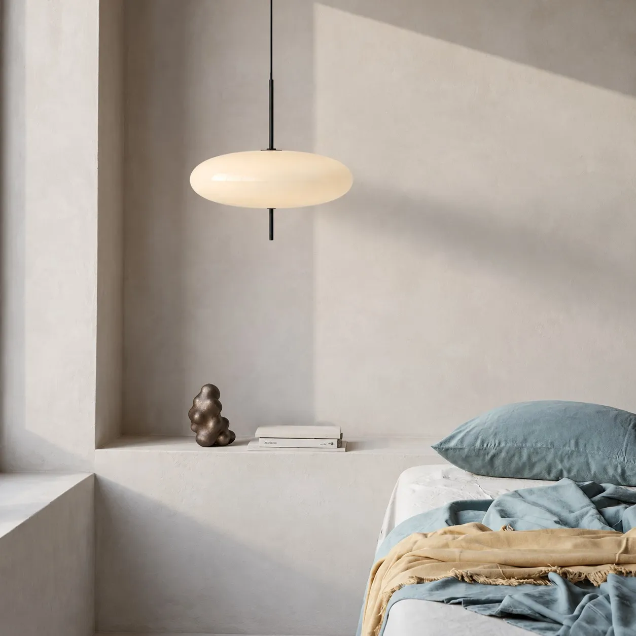 White elliptical pendant above a bed