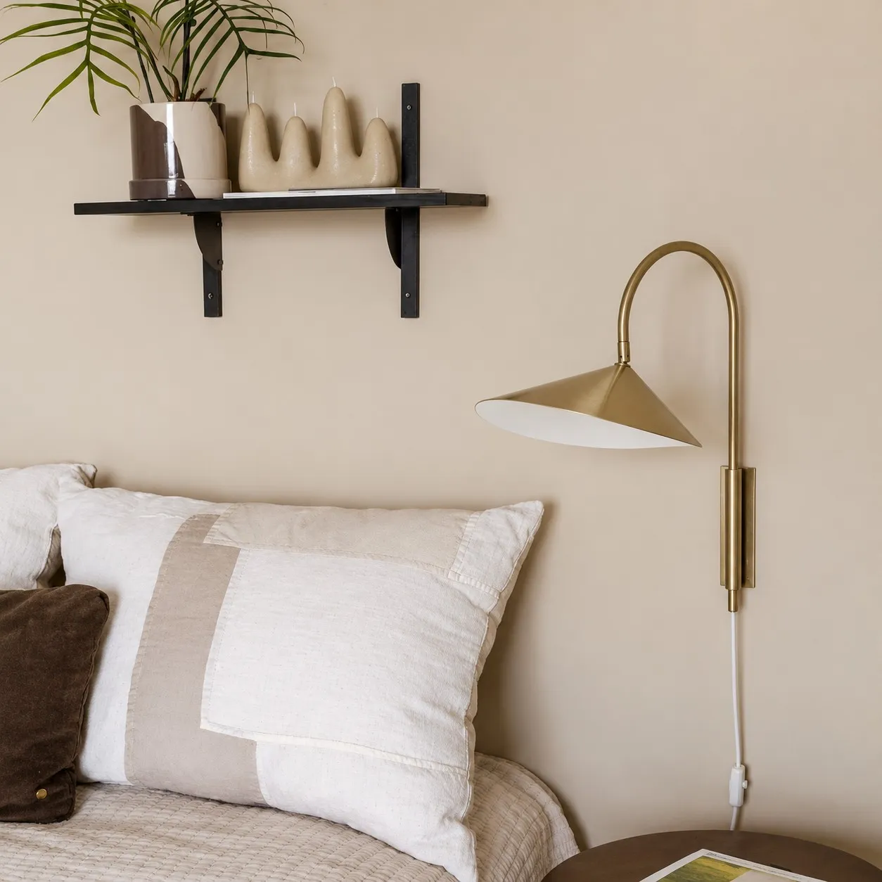 Bronze swivel wall lamp beside a bed