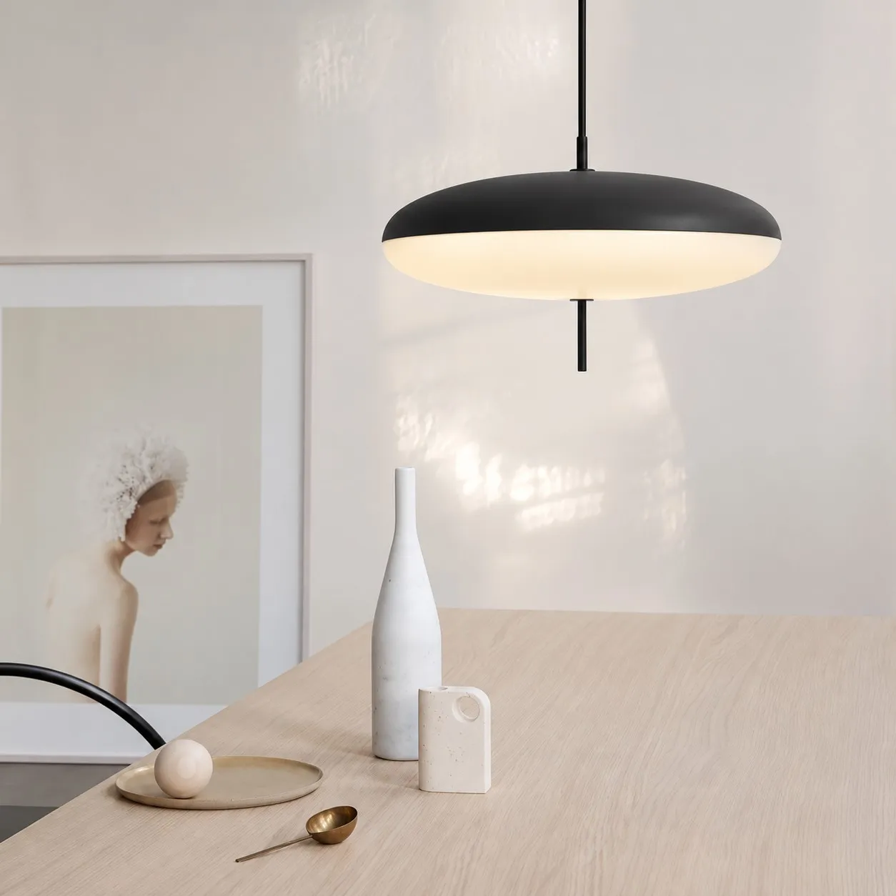 Black elliptical pendant above a wood table