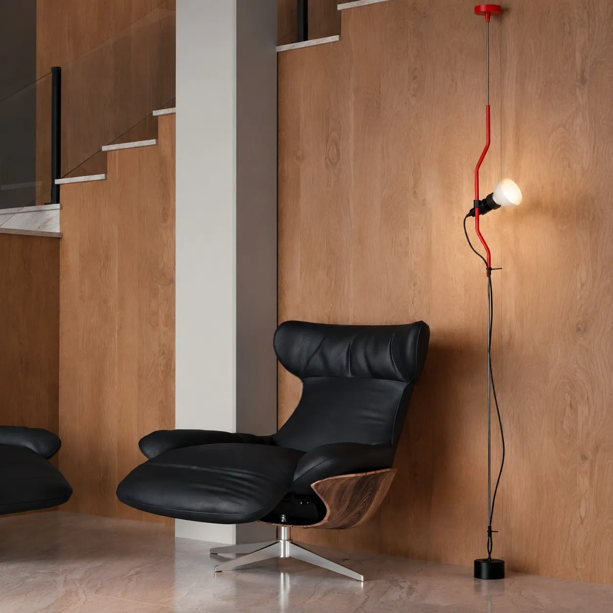 Red ceiling-to-floor lamp beside a lounge chair