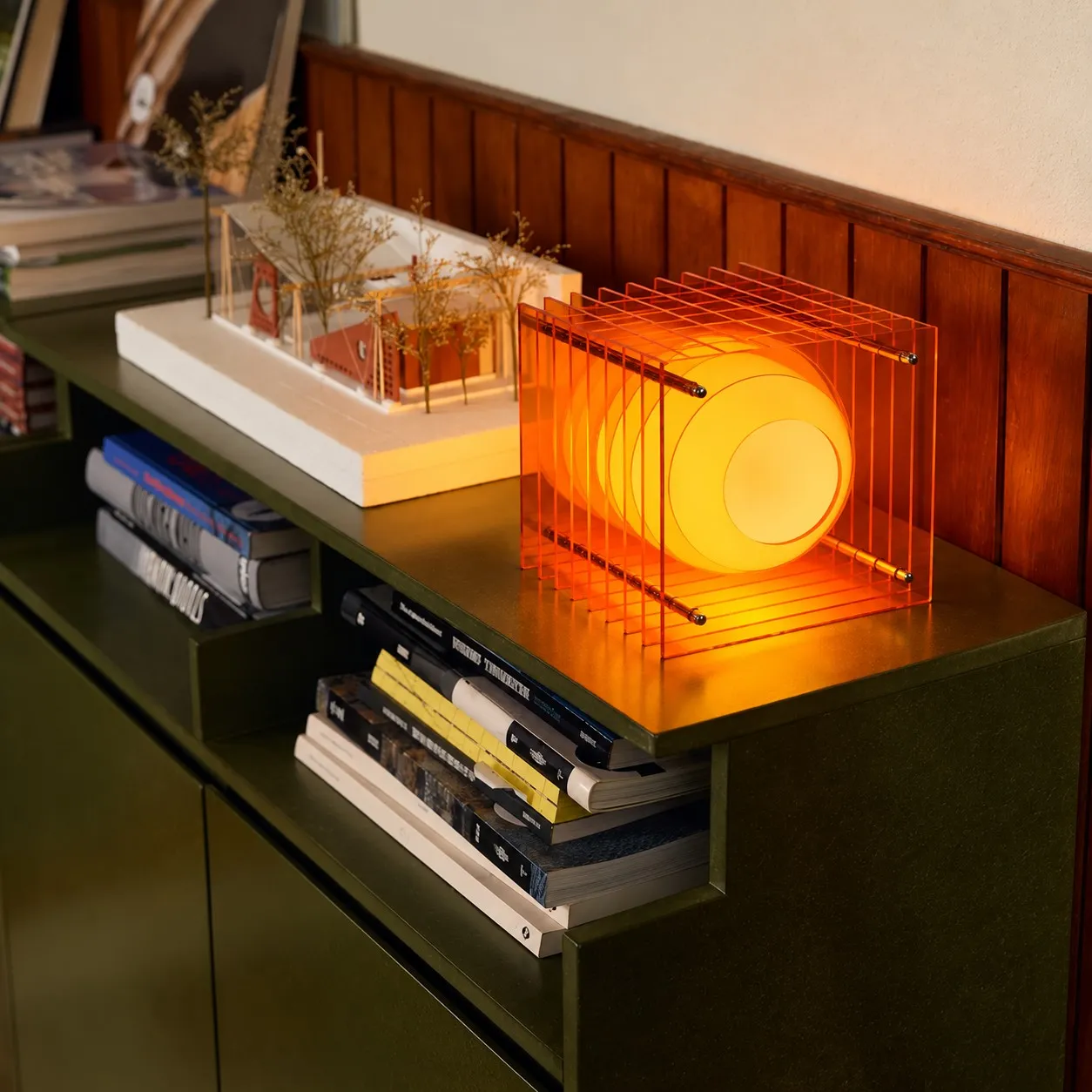 Orange acrylic cube lamp on a green cabinet