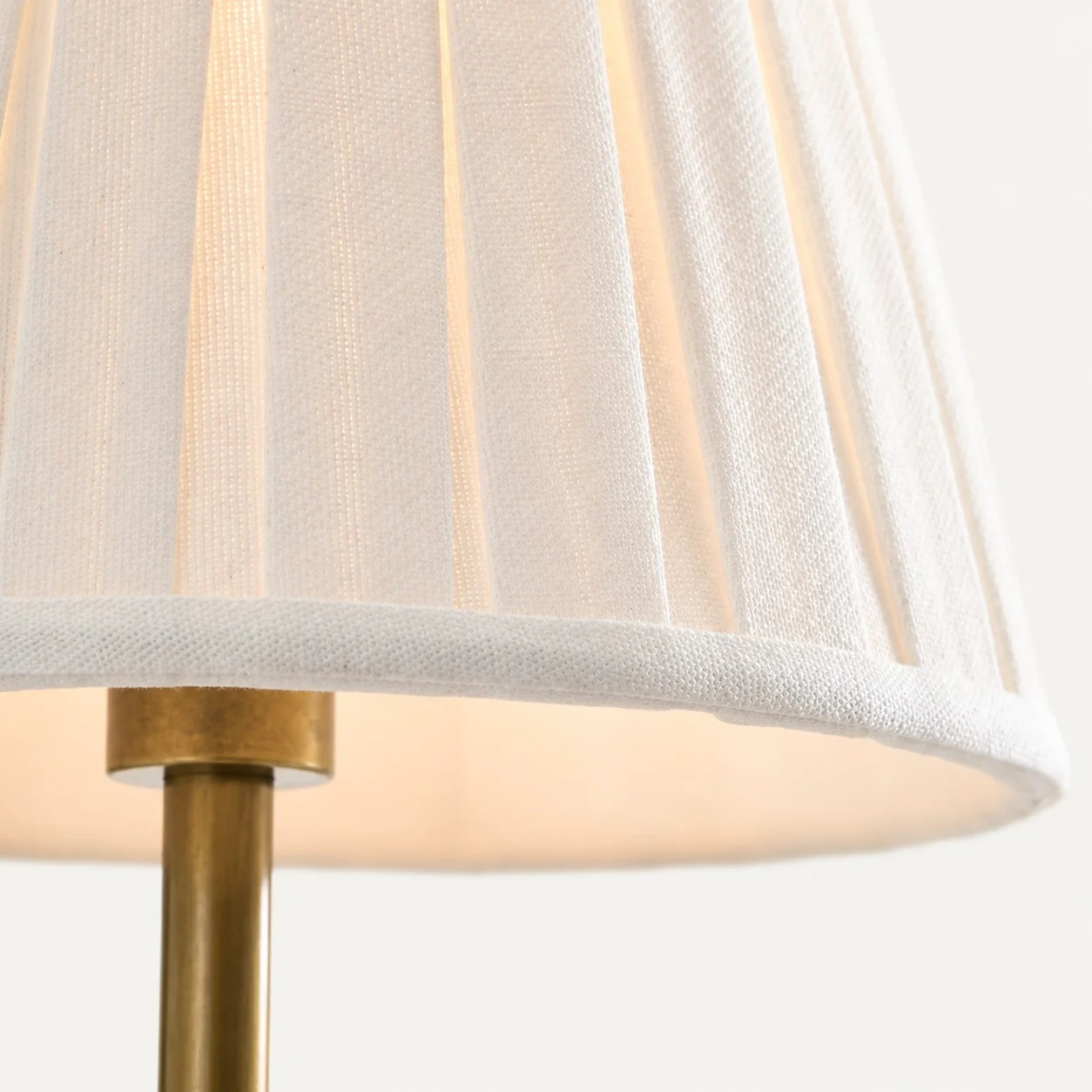 Lit white pleated linen shade on brushed brass collar