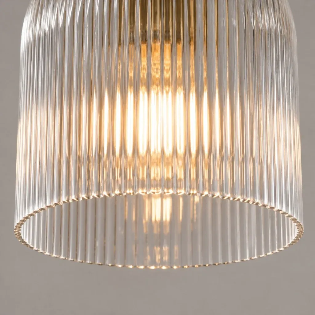 Open ribbed edge of a clear glass bell shade with warm light inside
