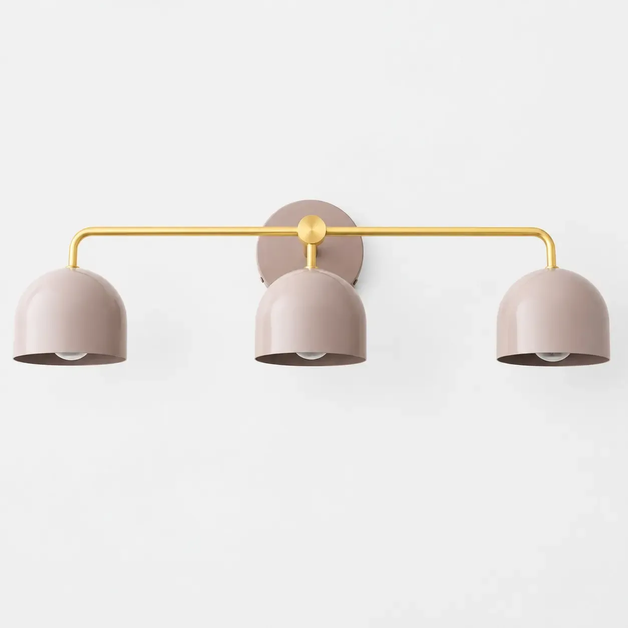 Brass three-head vanity sconce with mauve dome shades