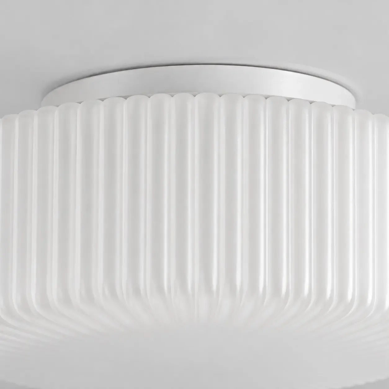 Close view of the white metal canopy meeting the ribbed glass shade